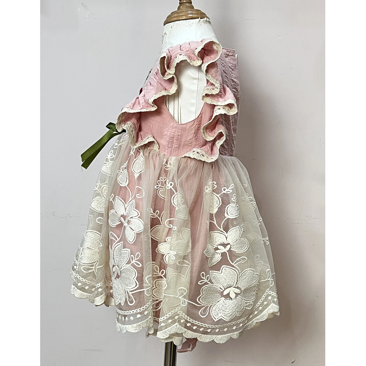 Pink dress with flutter sleeves and trimed with eyelet lace, has hand embroidery in the chest