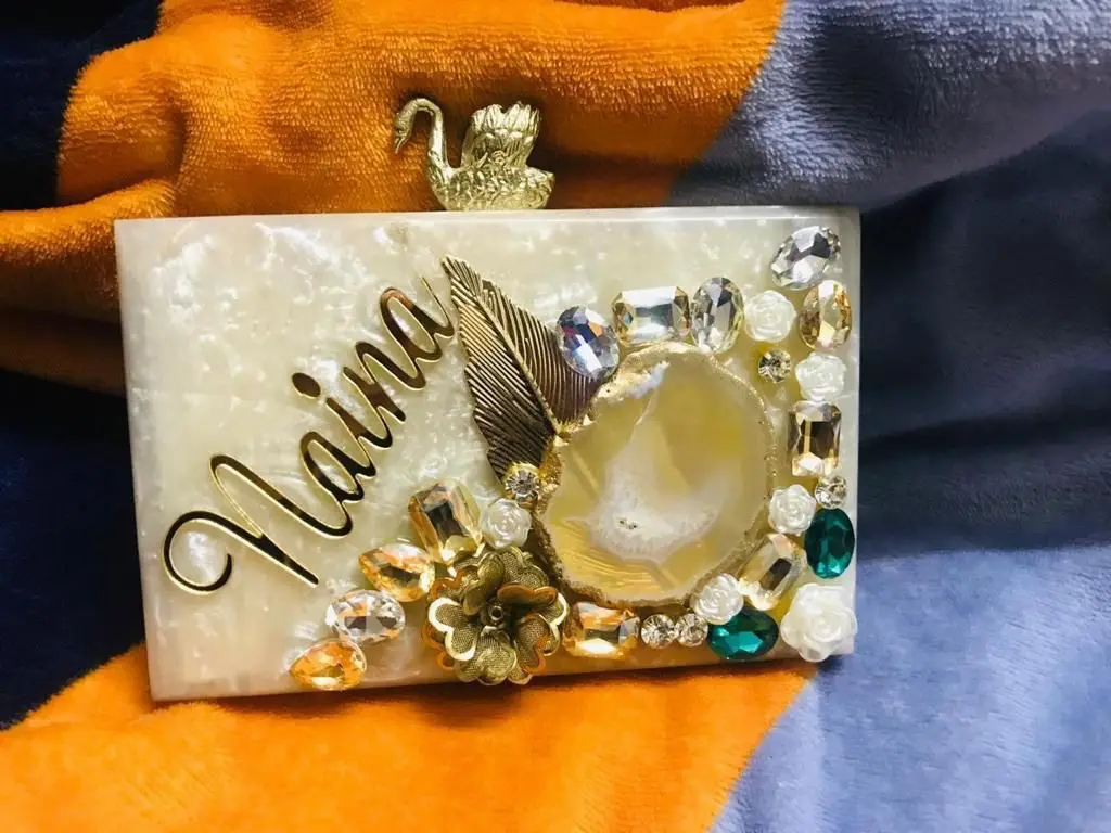 Featuring clutch in mother of pearl base with embedded rhinestones It has a gold chain sling, a magnetic closure.