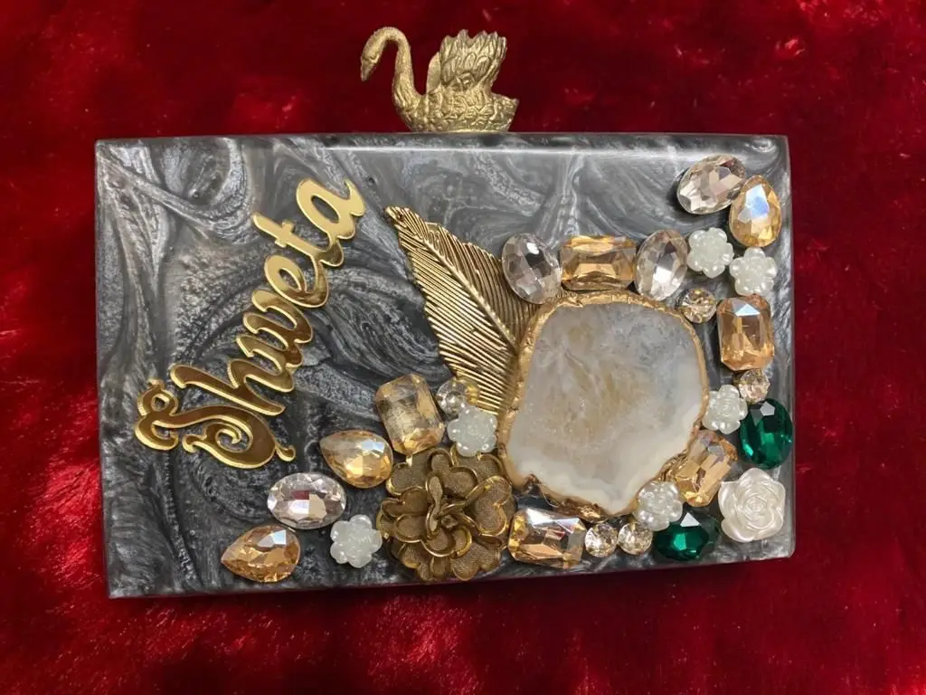 Featuring clutch in mother of pearl base with embedded rhinestones It has a gold chain sling, a magnetic closure.