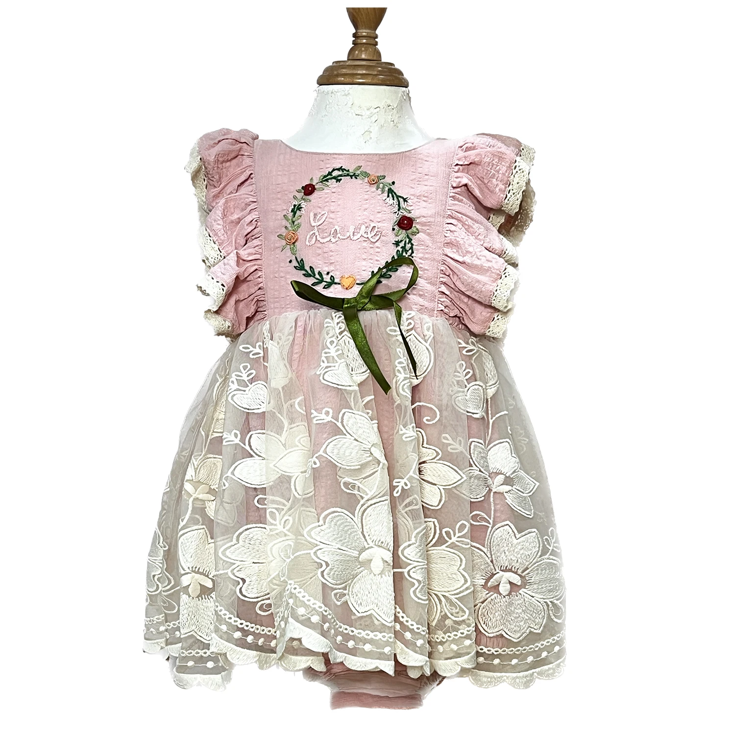Pink dress with flutter sleeves and trimed with eyelet lace, has hand embroidery in the chest