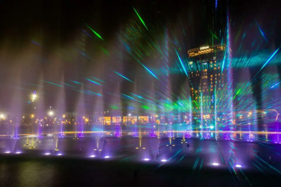 A large outdoor music and dancing water fountain show featuring laser lights, water screen mapping, video projections, fireworks