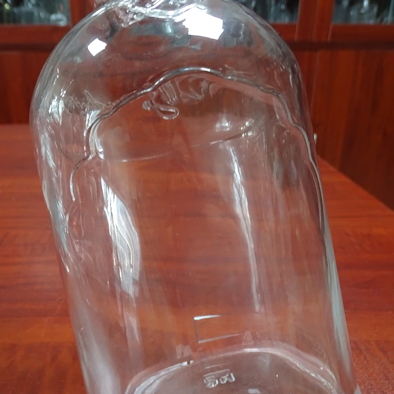 embossed custom brand cheap 1l glass bottle round for whiskey alcohol