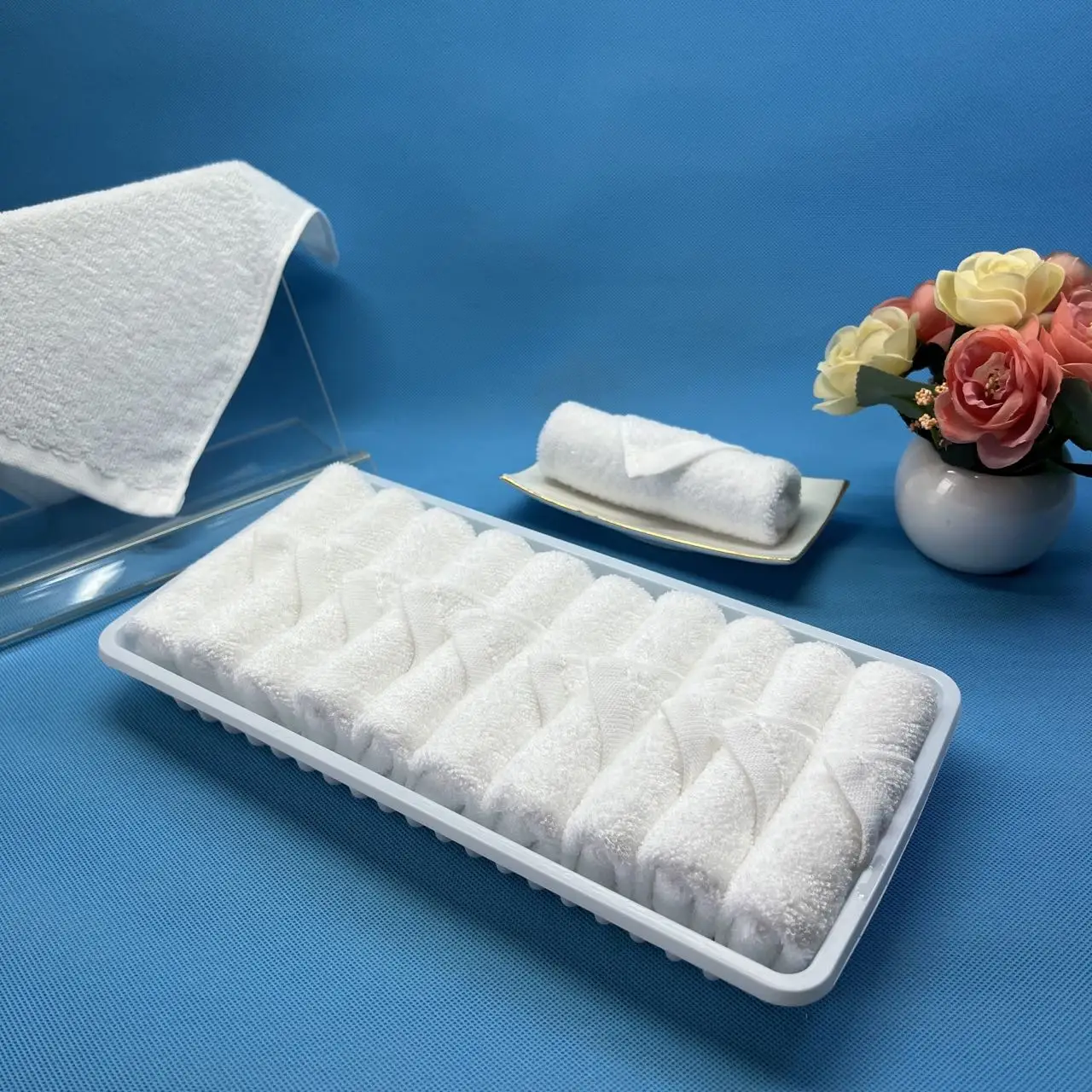 Rolled white disposable hot and cold face airline towels in tray