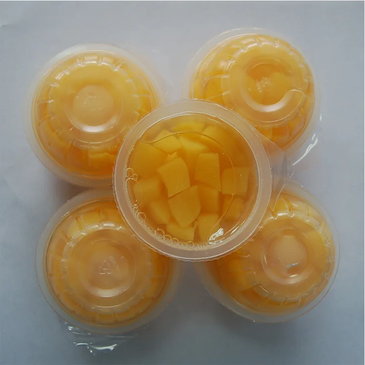 В пластиковых чашках с кубиками персика консервированный фруктовый бокал