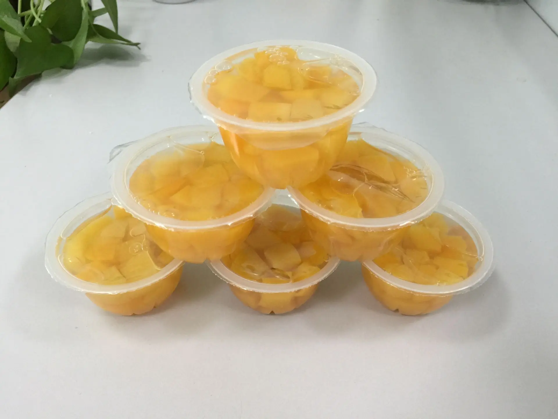 В пластиковых чашках с кубиками персика консервированный фруктовый бокал