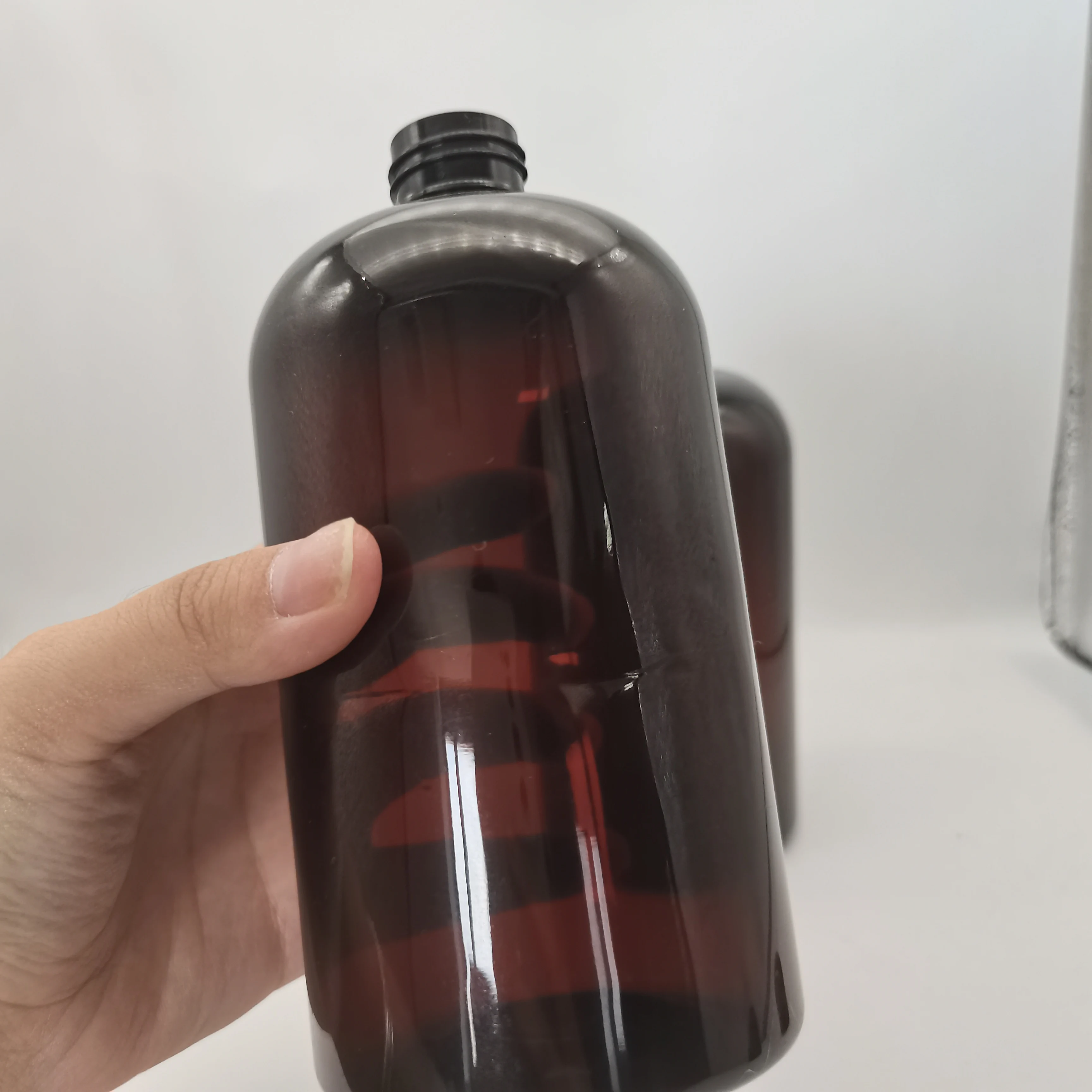 Dark amber Boston plastic bottle with black screw top and top