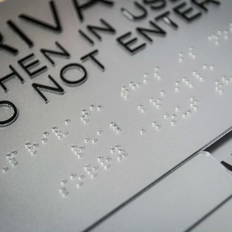 Emergency exit sign for Australian market with braille symbol