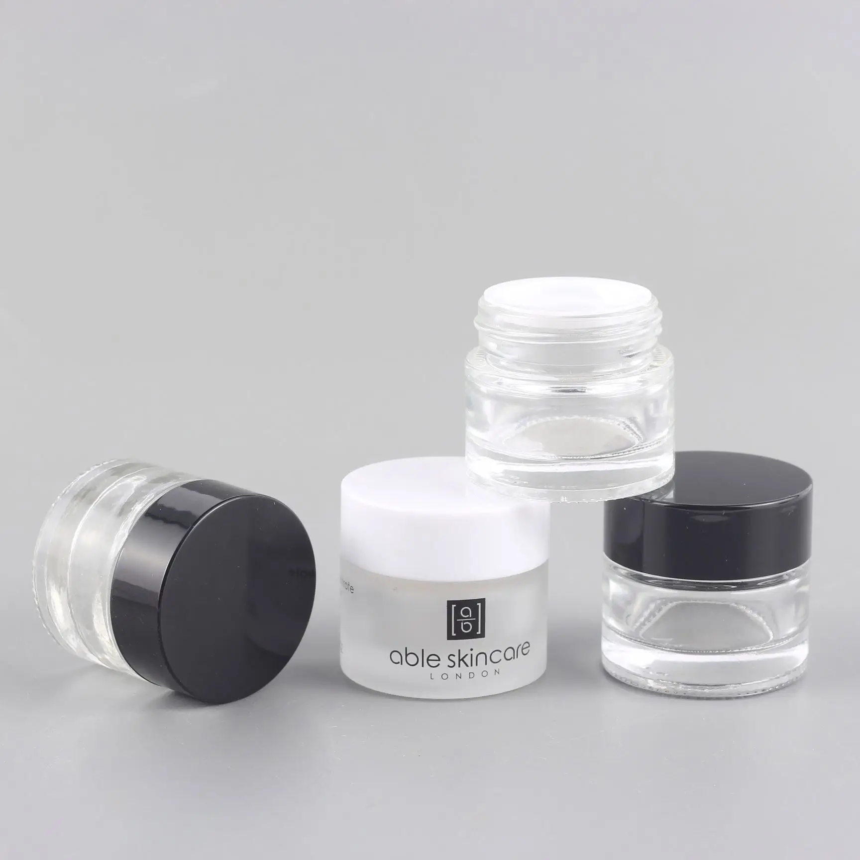 Chinese factory selling 10 ml transparent glass cream pot black plastic spiral lid