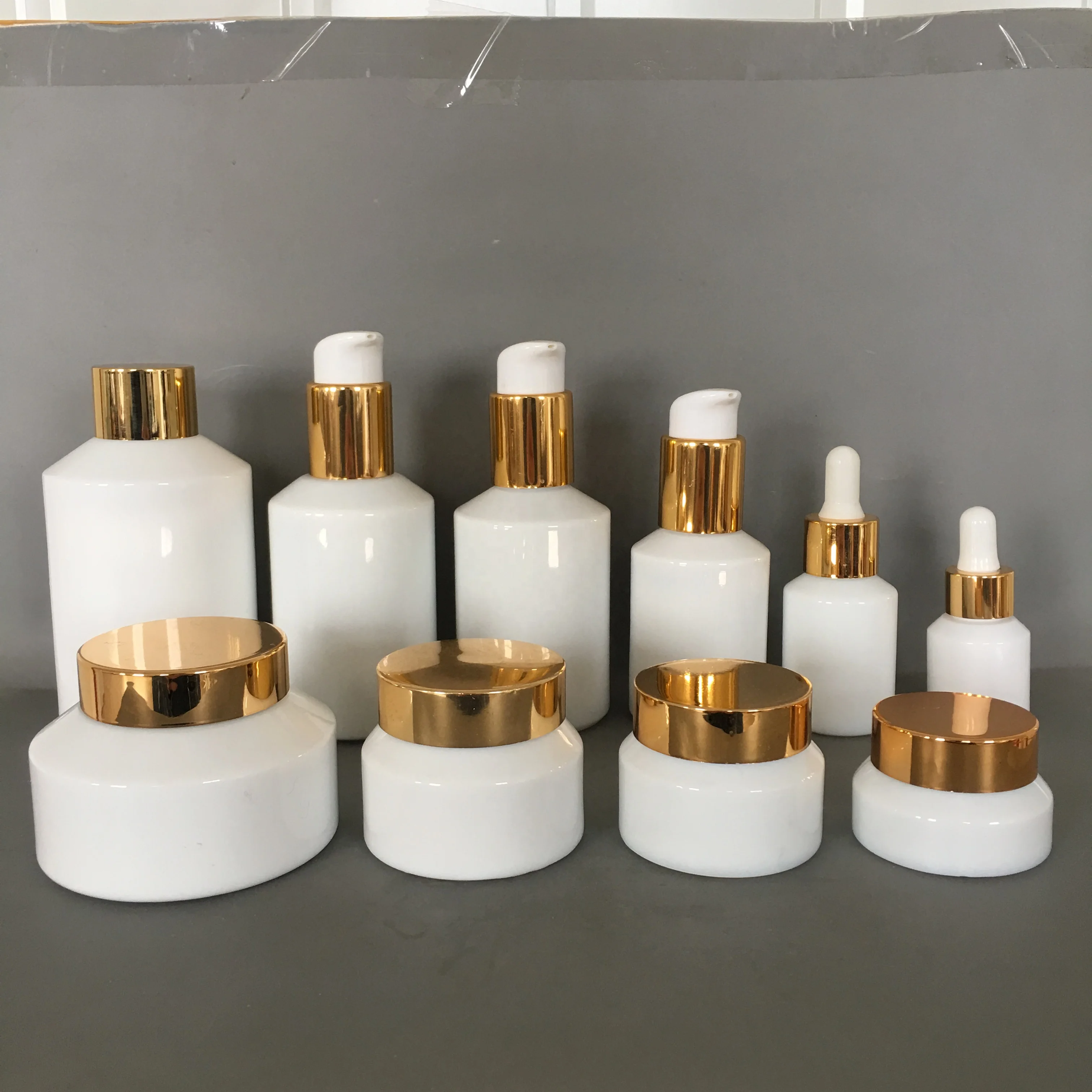 Cosmetic packaging slant shoulder white glass bottle and jar series with gold lid/pump/dropper cosmetic lotion bottle products