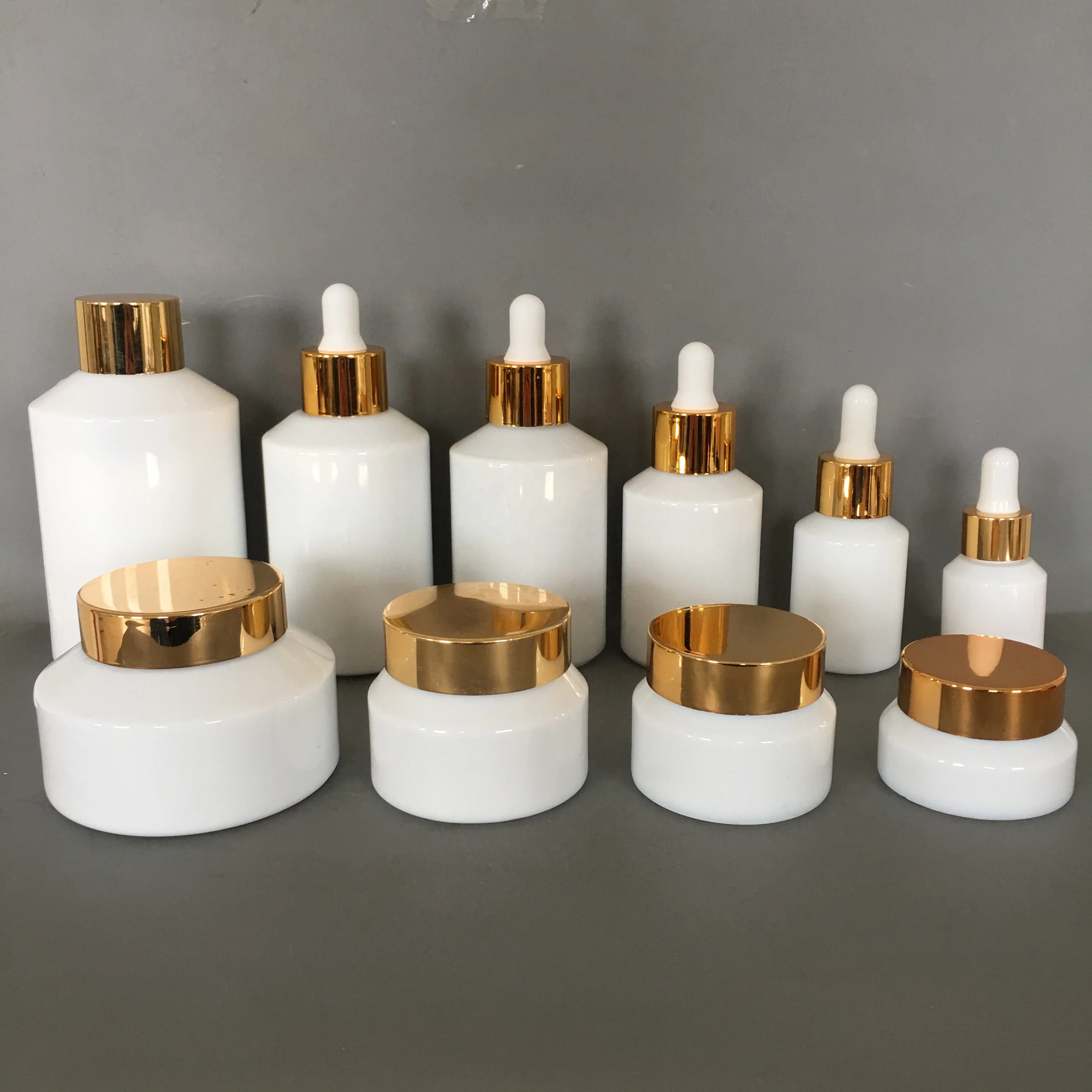Cosmetic packaging slant shoulder white glass bottle and jar series with gold lid/pump/dropper cosmetic lotion bottle products
