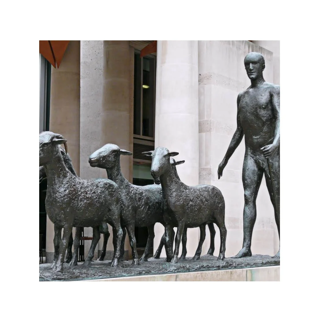 Bronze figure and goats sculpture statue on a square after rain next to cafe London in United Kingdom