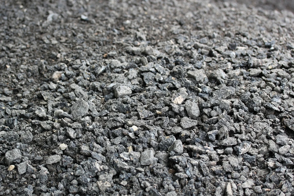  Свежеуложенный черный битумный асфальт с высокой кромкой до гравия показывающей конструкцию